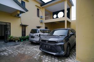 twee auto's geparkeerd voor een gebouw bij Urbanview Hotel St Faustina Lampung by RedDoorz in Kedaton