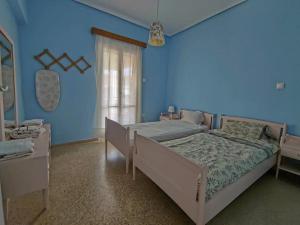una camera con due letti e una parete blu di Διαμέρισμα δίπλα στη θάλασσα, παραλία Μαρκοπούλου a Oropos
