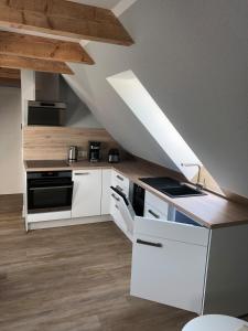 cocina con armarios blancos y techo en Ferienwohnung am Storchnest en Kenz