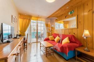 a living room with a red couch and a table at Apartamentos Los Delfines in El Médano