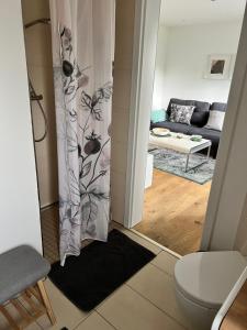 a bathroom with a toilet and a living room at BeeHome Euskirchen in Euskirchen