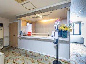 ein Wartezimmer mit einer Theke mit Blumen darauf in der Unterkunft Tabist Annex Matsumi in Beppu