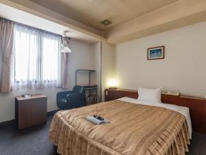 ein Hotelzimmer mit einem Bett und einem Stuhl in der Unterkunft Tabist Annex Matsumi in Beppu