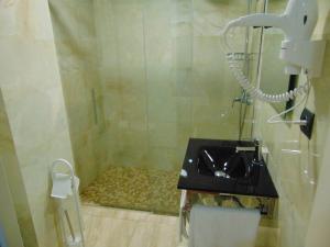 a bathroom with a shower with a sink and a phone at Hotel Aro'S in Casas Ibáñez