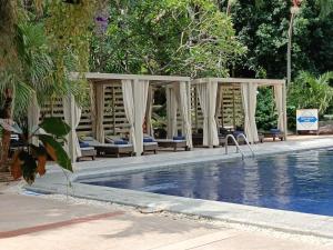 a swimming pool with chairs and a gazebo at Let's Hyde Pattaya Resort & Villas - Pool Cabanas in Pattaya North