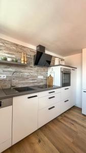 uma cozinha com armários brancos e um lavatório em CASA CASSAI - Casa Milo em Meiningen