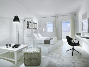 a white bedroom with a bed and a chair at Artemis Seaside Resort in Paliochori