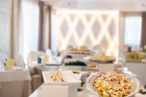 uma linha de buffet com pratos de comida numa mesa em Hotel Feldberg em Riccione