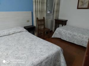 a hotel room with two beds and a chair at Hostal Fisterra in Lugo