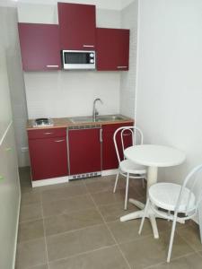 uma cozinha com armários vermelhos, uma mesa e cadeiras em Berenice Suite em Taranto