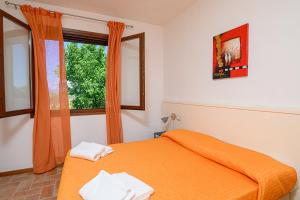 a bedroom with an orange bed and a window at Residenza Principina in Principina Terra +37 photos
