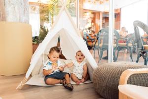 dos niños jugando en una tienda tipi en Hotel Brioni Mare, en Lido di Jesolo