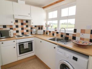 a kitchen with white cabinets and a sink at Bumblebee Cottage in Stranraer