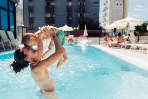 Dos mujeres están jugando en una piscina en Hotel Brioni Mare, en Lido di Jesolo
