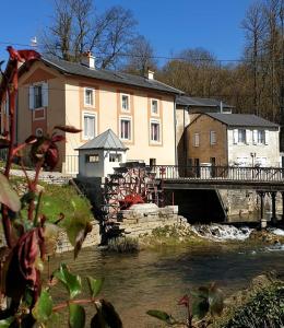 een brug over een rivier voor een gebouw bij Gîte du Domaine de la Forge in Boncourt-sur-Meuse