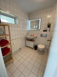 ein weiß gefliestes Badezimmer mit Toilette und Waschbecken in der Unterkunft City-Appartement 12.3. in Zwickau
