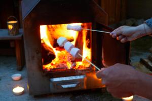 a person is cooking food in a fireplace at Pinewood Park - Tipis, Hot Tubs and Lodges in Scarborough