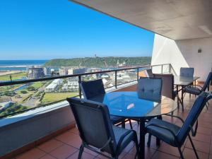 a balcony with tables and chairs and a view of the ocean at Accommodation Front - Immaculate 4 Sleeper with Ocean & Harbour Views in Durban