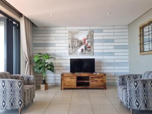 a living room with a tv and two chairs at Accommodation Front - Immaculate 4 Sleeper with Ocean & Harbour Views in Durban +16 photos