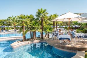 a group of people sitting at a table by a pool at Grand Hotel Terme & Spa in Montegrotto Terme