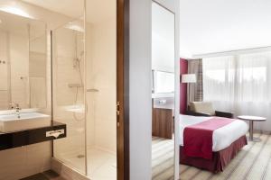 a bathroom with a bed and a shower and a sink at Holiday Inn Lille Ouest Englos, an IHG Hotel in Englos
