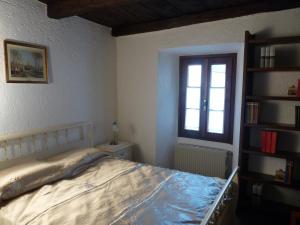 a bedroom with a bed and a window and a book shelf at Apartments Cusius and Horta in Orta San Giulio