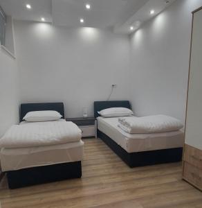 Habitación con 2 camas, paredes blancas y suelo de madera. en Apartman Dona, en Banja Luka