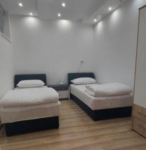 2 Betten in einem Zimmer mit weißen Wänden und Holzböden in der Unterkunft Apartman Dona in Banja Luka