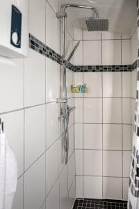 um chuveiro na casa de banho com paredes em azulejos brancos em Ferienhaus Therese em Kobern-Gondorf