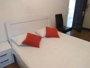 2 almohadas rojas sentadas en una cama blanca con silla en Old Capital, en Mtskheta