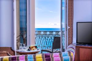 a room with a balcony with a view of the ocean at Hôtel West End Promenade in Nice