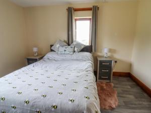 a bedroom with a bed with a white comforter and a window at The Cottage in Talacre