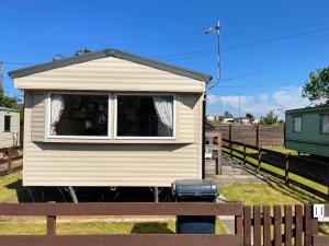 una pequeña casa sentada en la parte superior de un banco de madera en Two Bedroom Willerby Parkhome in Uddingston, Glasgow, en Uddingston