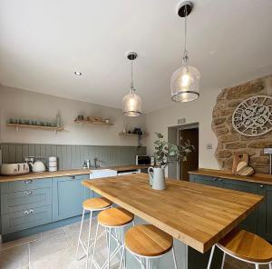 a kitchen with blue cabinets and a wooden table with stools at Mulberry House - Morpeth Town Centre - Hot Tub in Morpeth