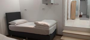 a small bedroom with a bed and a mirror at Apartman Dona in Banja Luka +1 photo