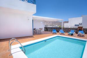 einen Pool mit blauen Stühlen und einem Tisch in der Unterkunft VV Mapaluca MiniGolf by HH in Playa Blanca