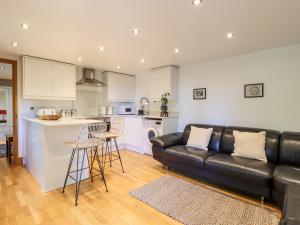 a living room with a black leather couch and a kitchen at Willow Cottage in Dartford