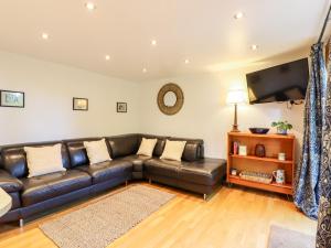 a living room with a leather couch and a flat screen tv at Willow Cottage in Dartford