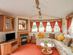 a living room with a couch and a tv at Ty Newydd Caravan in Pwllheli
