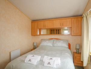 a bedroom with a bed with two towels on it at Ty Newydd Caravan in Pwllheli