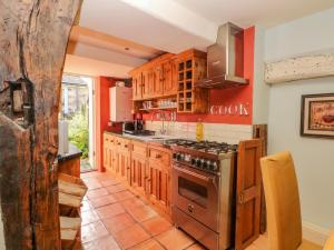 a kitchen with wooden cabinets and a stove top oven at Bobbin Cottage in Bakewell