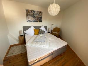 1 dormitorio con 1 cama blanca grande con lámpara de araña en Ferienwohnung "Boddenland", en Barth