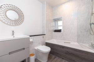 a white bathroom with a tub and a toilet and a sink at City centre 2 bedroom flat with on site parking in Perth
