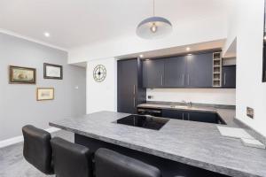 a kitchen with a large counter with black chairs at City centre 2 bedroom flat with on site parking in Perth
