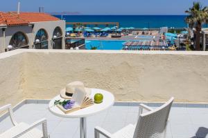 a table with a hat and a book on it next to a pool at Europa Beach Hotel & Spa in Hersonissos