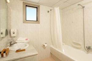 a white bathroom with a sink and a shower at Europa Beach Hotel & Spa in Hersonissos
