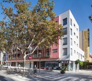 un edificio en una calle de la ciudad con un árbol en Durlet Rambla Mar Apartments en Barcelona