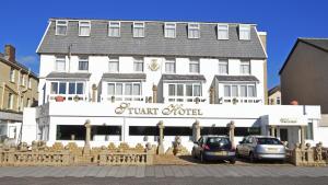 un grand bâtiment blanc avec des voitures garées devant lui dans l'établissement Stuart hotel, à Blackpool