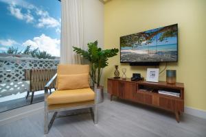 a living room with a tv and a chair at Luxury 1 bed apartment near Seven Mile Beach at The Grove - Villa Pina Colada in Upper Land