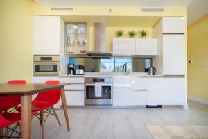 a kitchen with white cabinets and a table with red chairs at Luxury 1 bed apartment near Seven Mile Beach at The Grove - Villa Pina Colada in Upper Land